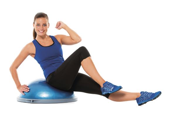 Frau trainiert mit Balance-Board und Beinheben, Fitness-Workout zu Hause.