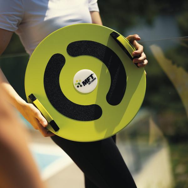 Person hält gelbes Balance-Board mit Griffen und schwarzer rutschfester Oberfläche.