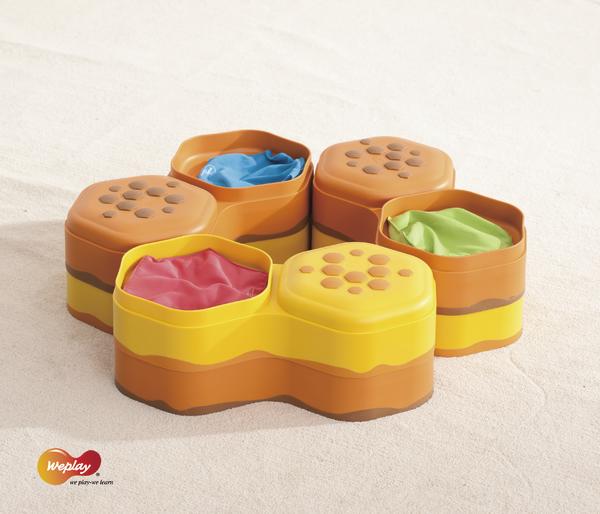 Bunte Sandspielzeug-Formen in Wabenstruktur mit buntem Sand auf Sanduntergrund.