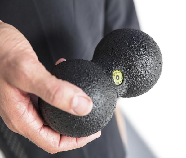 Hand hält schwarzen Faszienball zur Muskelentspannung und Selbstmassage.