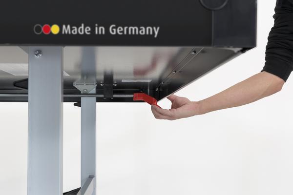 Hand betätigt roten Hebel an Maschine mit "Made in Germany" Schriftzug.