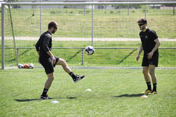 Zwei Fußballspieler beim Pass- und Ballkontrolltraining auf grünem Fußballplatz.