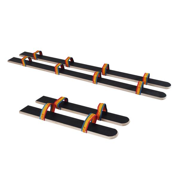 Zwei Paar Holzlaufstelzen mit bunten Fußriemen für Kinder, isoliert auf weißem Hintergrund.