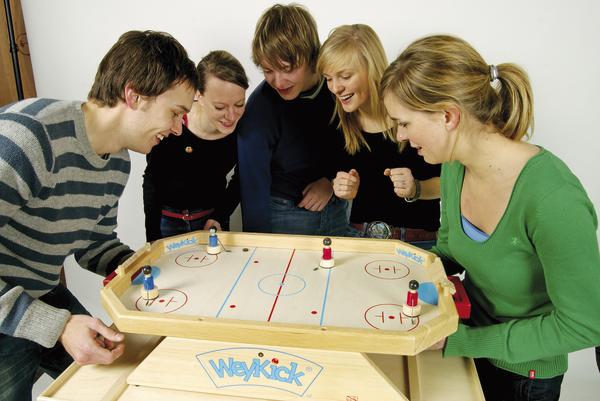 Fünf junge Erwachsene spielen begeistert Tischhockey an einem WeyKick Spieltisch.