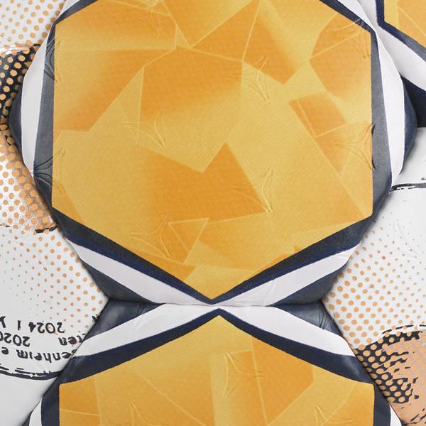Detailaufnahme der Balloberfläche mit orangefarbenem, geometrischem Muster. Sichtbar sind die strukturierte Oberfläche, schwarze und weiße Konturlinien zwischen den Ballsegmenten sowie weiße Segmente mit grafischen Druckelementen.