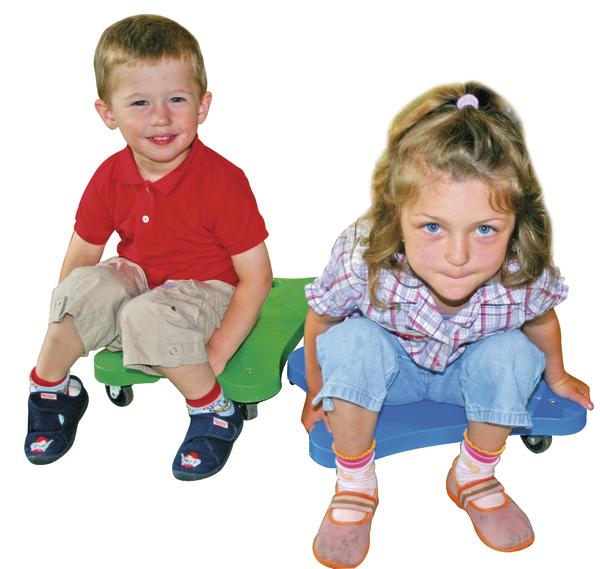 Junge und Mädchen sitzen auf bunten Rollbrettern und schauen in die Kamera.