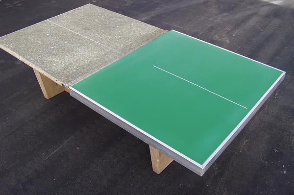 Outdoor-Tischtennisplatte mit grünem Spielfeld und grauer Spielfeldhälfte auf Asphaltboden.