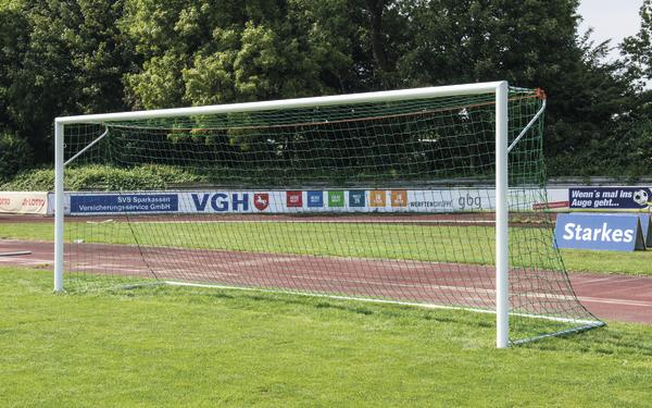 Fußballtor auf grünem Spielfeld mit Werbebannern im Hintergrund.