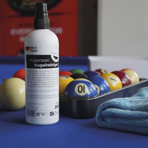 Kugelreiniger-Spray neben Billardkugeln und Mikrofasertuch auf Tisch