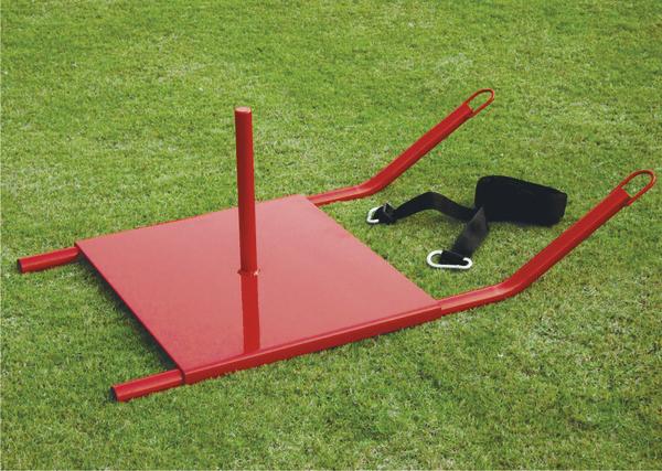 Rotes Trainingsgerät zum Ziehen auf Grasfläche, mit Gurt und Griffen für Krafttraining.