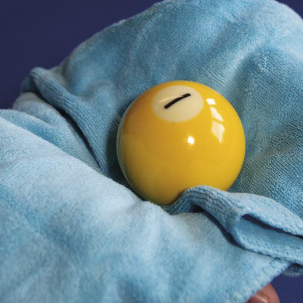 Gelbe Billardkugel wird mit Mikrofasertuch gereinigt