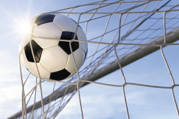 Fußball trifft ins Tornetz bei sonnigem Himmel, Symbol für Torerfolg im Spiel.