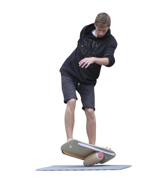 Junger Mann balanciert auf einem Balance-Board mit Zylinder auf weißem Hintergrund.