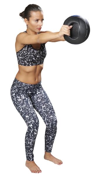 Frau in Sportkleidung macht Kettlebell-Übung für Kraft und Balance.