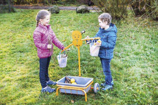 Mädchen und Junge sammeln Äpfel im Garten mit TopTrike Waage und Eimern.
