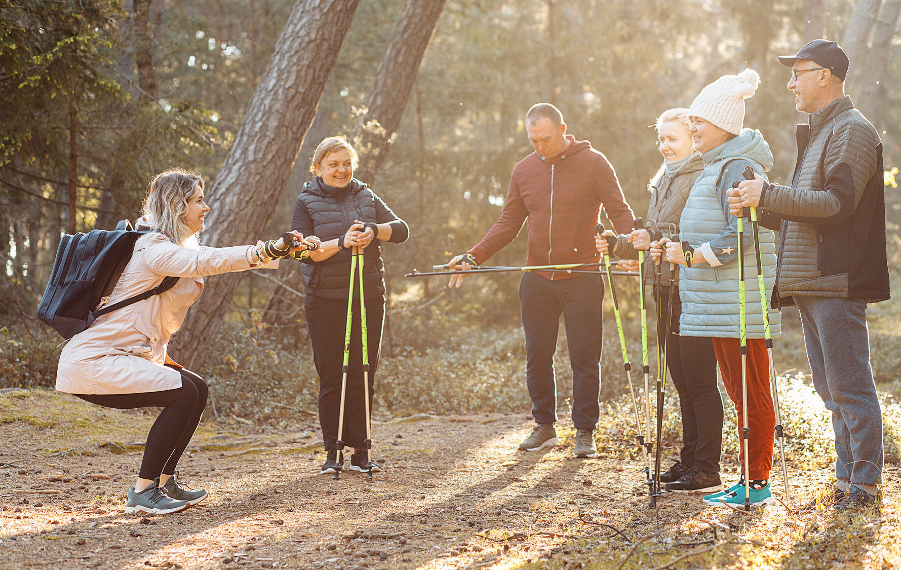 sechs Menschen stehen im Kreis mit Nordic Walking Stöcken und stretchen sich