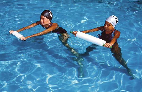 Kinder beim Schwimmtraining mit Schwimmhilfen im Pool bei Sonnenschein