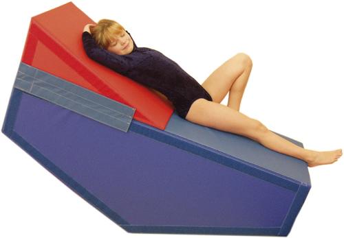Kind liegt entspannt auf farbigem Schaumstoff-Kletterwürfel in Turnkleidung.