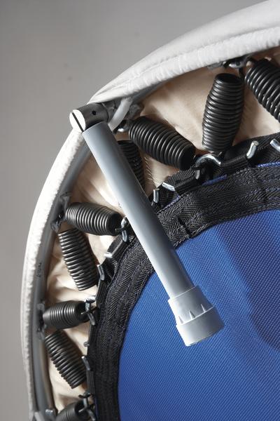 Mini-Trampolin mit Federn und grauem Stützrohr, Nahaufnahme auf grauem Hintergrund.