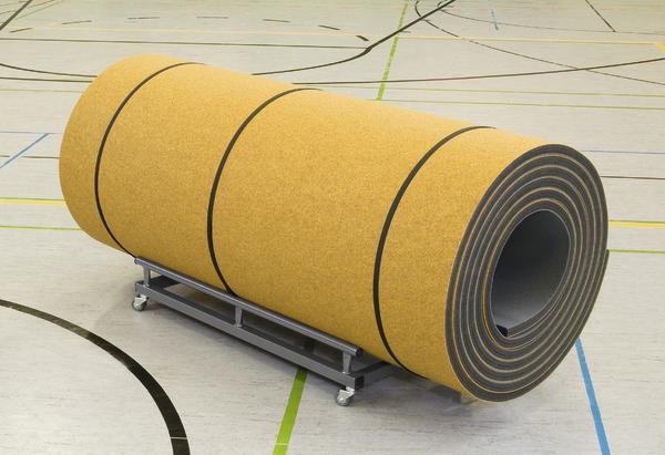 Große gelbe Sportbodenrolle auf Transportwagen in Sporthalle mit Linienmarkierungen.