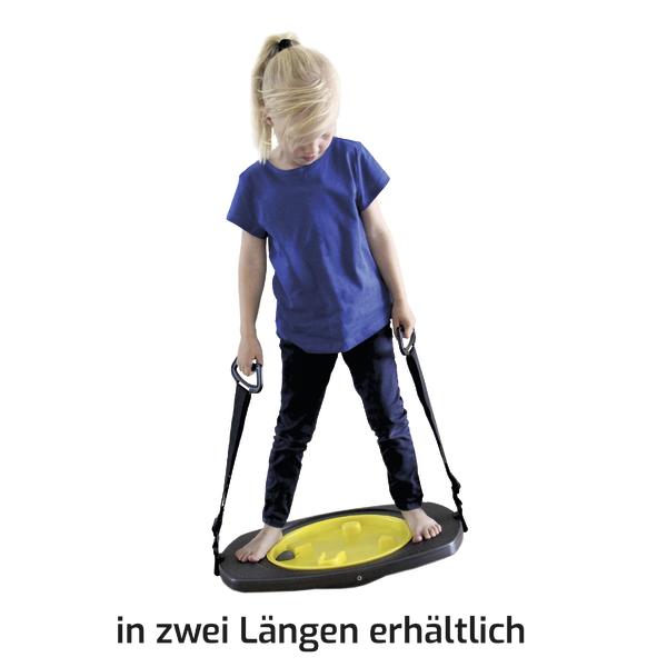 Kind steht auf Balancierbrett mit Griffen, Gleichgewichtstraining für Kinder.