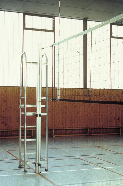 Volleyballnetz und Schiedsrichterstuhl in einer leeren Sporthalle mit Holzverkleidung.