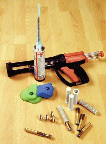 Kartuschenpistole mit Dichtstoff, Düsen und Zubehör auf Holzuntergrund für Abdichtungsarbeiten.