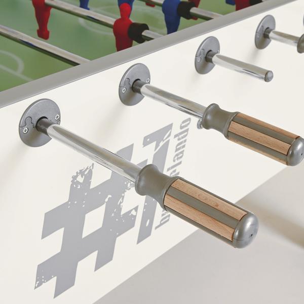 Detailaufnahme eines Tischkickers mit Metallstangen, Holzgriffen sowie roten und blauen Spielfiguren.