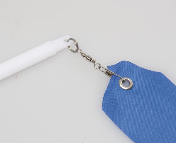 Weißer Stab mit blauem Wimpel, verbunden durch Metallwirbel und Öse auf weißem Hintergrund.