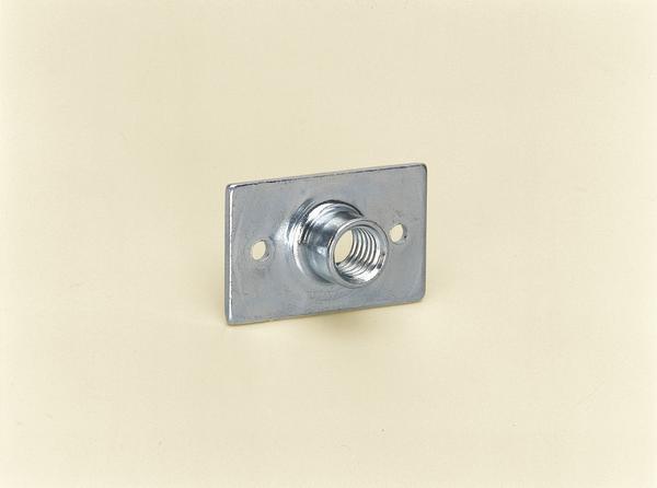 Metallische Gewindemutter mit Befestigungsplatte an einer hellen Wand montiert.