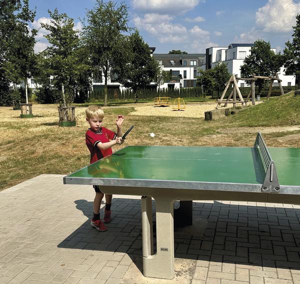 Kind spielt mit dem SPORTCO Tischtennisschläger School an einer Outdoor-Tischtennisplatte im Freien.