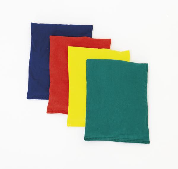 Vier bunte Bohnensäckchen in Blau, Rot, Gelb und Grün auf weißem Hintergrund.