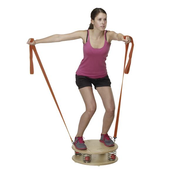 Frau trainiert Balance und Kraft mit Widerstandsband auf Feder-Balance-Board.