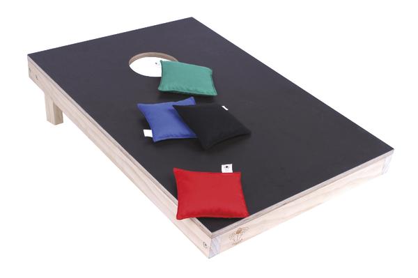Schwarzes Cornhole-Spielbrett mit vier bunten Wurfsäckchen in Rot, Blau, Schwarz und Grün.
