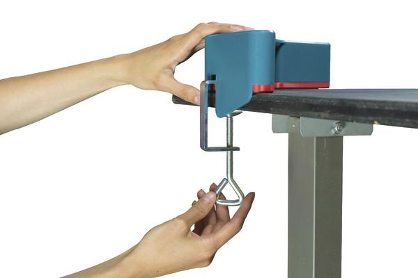 Hände befestigen einen blauen Tischklemmlaser an einer Tischplatte für präzise Messungen.