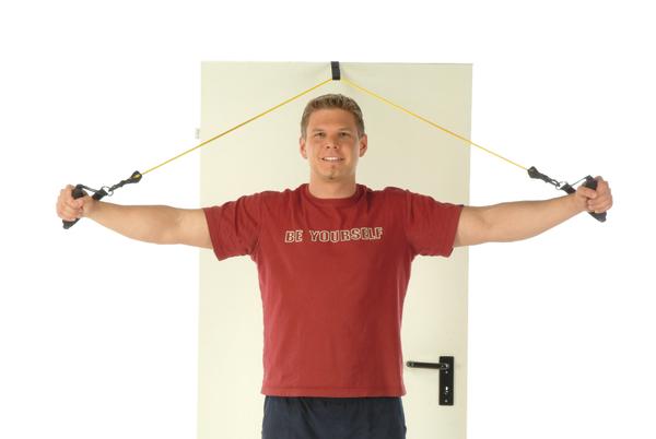 Mann trainiert mit Widerstandsbändern an einer Tür, trägt rotes T-Shirt "Be Yourself".