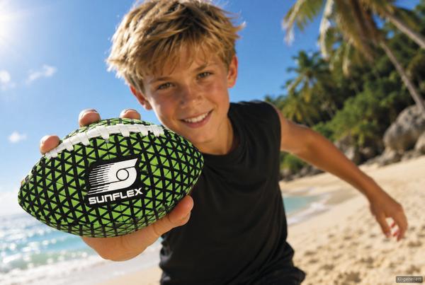 Junge am Strand mit einem grün-schwarzen Sunflex Spielball in der Hand.