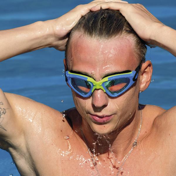 Mann mit Schwimmbrille im Wasser, der sich die nassen Haare zurückstreicht.
