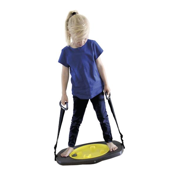 Kind steht auf Balancierbrett mit Griffen, trainiert Gleichgewicht und Koordination.