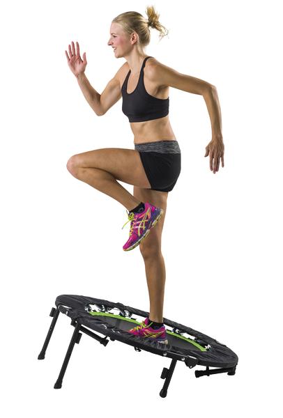 Frau trainiert auf Mini-Trampolin mit Sportkleidung und bunten Laufschuhen.