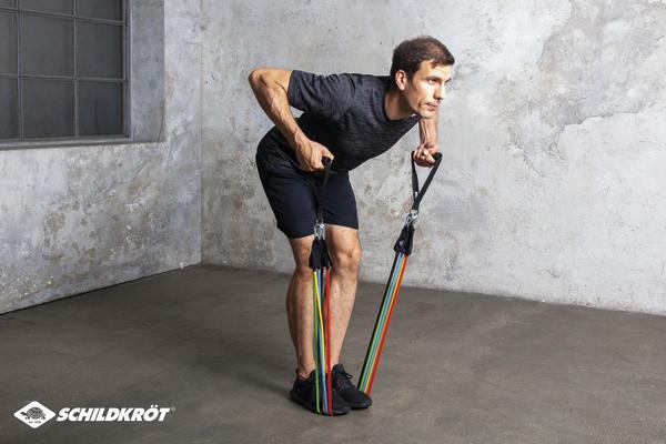 Mann trainiert mit Widerstandsbändern im Fitnessraum für Kraft und Ausdauer.