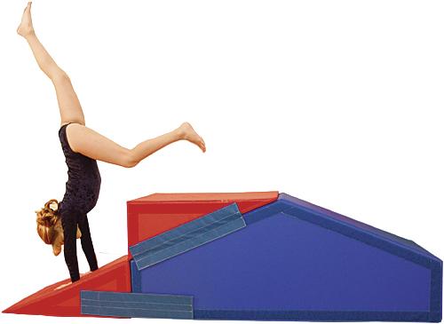 Kind macht Handstand auf buntem Turngerät aus Schaumstoff in Sporthalle.