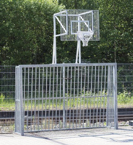 Metalltor mit integriertem Basketballkorb auf einem Außenplatz vor grünem Wald.
