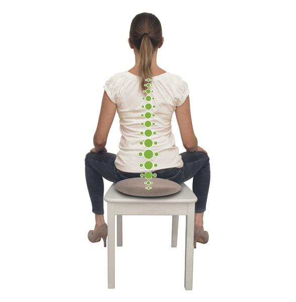 Frau sitzt auf Stuhl mit Sitzkissen, grüne Punkte markieren Wirbelsäule für ergonomische Haltung.