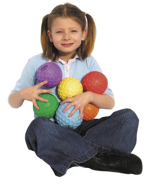 Mädchen sitzt mit bunten Spielbällen in den Armen auf weißem Hintergrund.