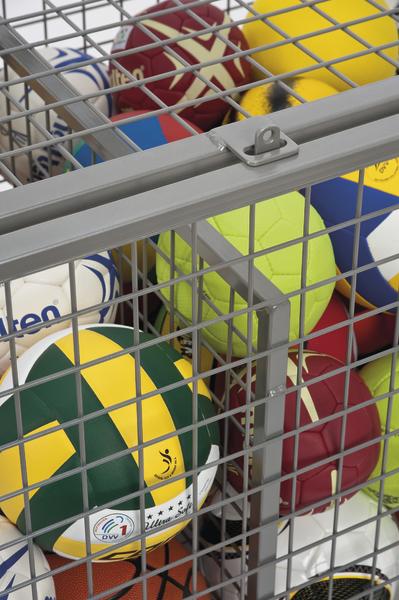 Verschiedene bunte Sportbälle in einem grauen Metallgitter-Aufbewahrungskorb.