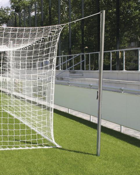 Fußballtor mit weißem Netz auf grünem Kunstrasen vor Tribüne im Freien.