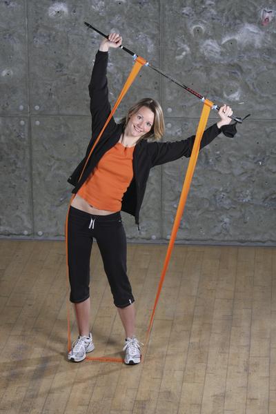 Frau macht Dehnübungen mit Widerstandsband und Stab in Fitnessstudio.