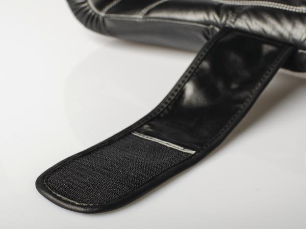 Schwarzer Klettverschlussriemen an gepolsterten Boxhandschuhe, Nahaufnahme auf weißem Hintergrund.