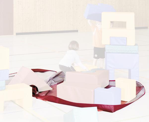 Kinder spielen mit großen bunten Schaumstoffbausteinen in einer Turnhalle.